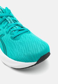 Baskets de course turquoise avec un dessus en maille texturée, des lacets et une semelle intermédiaire blanche rembourrée. Semelle extérieure en caoutchouc avec un motif de traction noir.