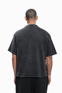 Zwart katoenen T-shirt met een relaxte pasvorm, korte mouwen en een ronde hals. Voorzien van een gewassen textuur en contrasterende stiksels.