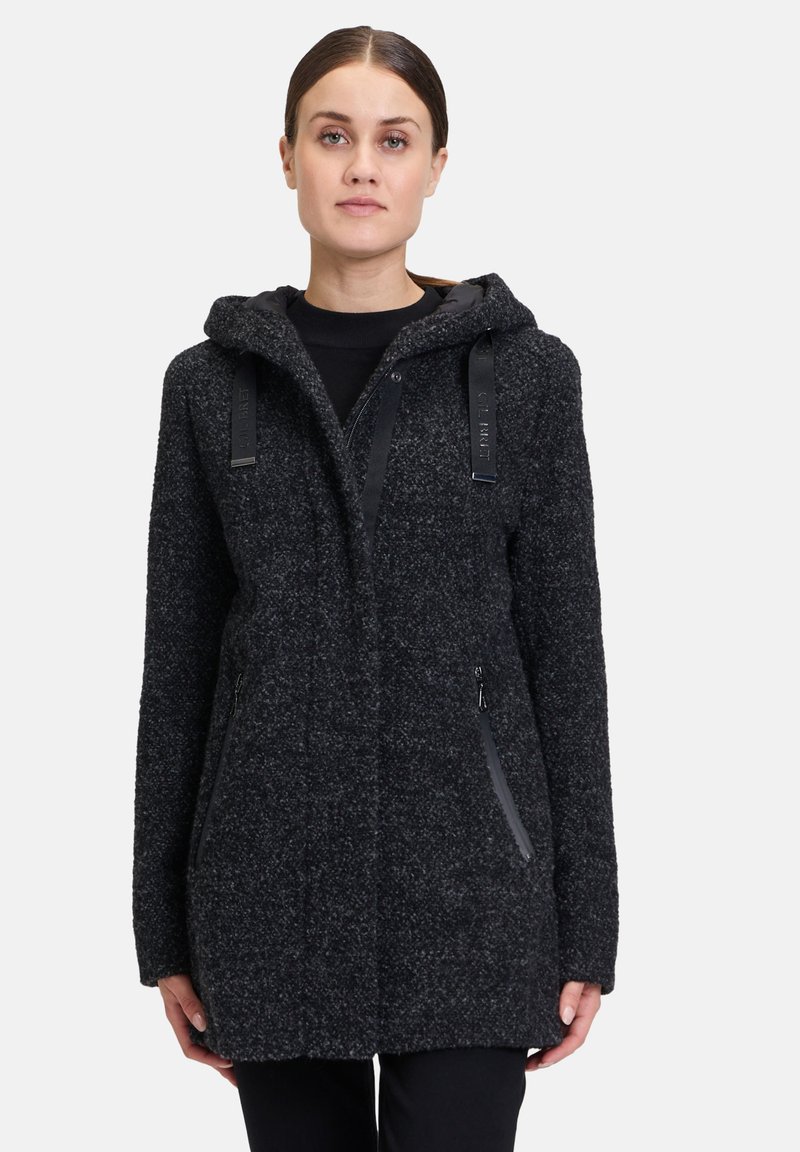 Czarny płaszcz z kapturem wykonany z teksturowanej tkaniny o luźnym kroju, z czarnymi zamkami błyskawicznymi po bokach i regulowanymi paskami na kapturze.