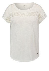 Bílý krátký rukáv tričko s texturovanou tkaninou a krajkovými detaily přes ramena. Zaoblený výstřih a zakřivený lem.