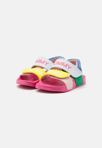 Kleurvolle sandalen met roze, gele, groene en blauwe secties, voorzien van twee verstelbare klittenbandsluitingen met de labels "TOMMY" en "HAGER."