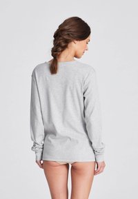 Graues Langarmshirt aus weichem Baumwollmaterial, mit einem lässigen Schnitt und Rundhalsausschnitt, ausgestattet mit gerippten Bündchen und Nähten, das für Komfort entworfen wurde.