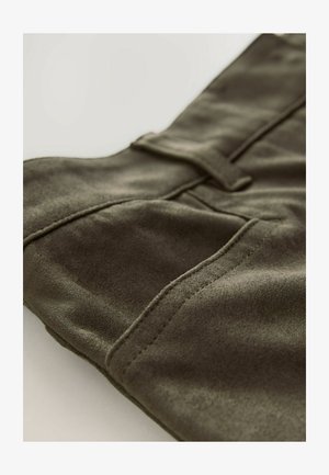 Material textil de culoare verde măslin, moale, cu o textură netedă; are cusături închise și un detaliu de buzunar mic cu clapetă. Potrivit pentru diverse stiluri casual.