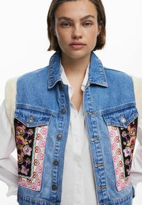 Denimweste mit gestickten Blumenmustern in lebhaften Farben auf schwarzem Stoff. Knöpfe und ein mit Fell verziertes Schulterdetail sind enthalten.