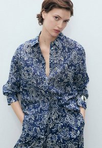 Camicia a maniche lunghe blu navy con motivo paisley. Realizzata in tessuto leggero, con maniche arrotolabili e una vestibilità rilassata.