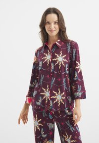 Katoenen pyjama's in diep bordeauxrood met zon- en vlinderpatronen, voorzien van een blouse met kraag en 3/4 mouwen, afgewerkt met een roze hartdetail.