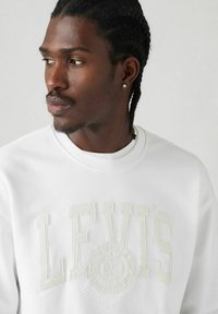 Sudadera blanca con el logotipo "LEVI'S" en relieve, escote redondo y mangas largas. Textura suave con un detalle de marca sutil.