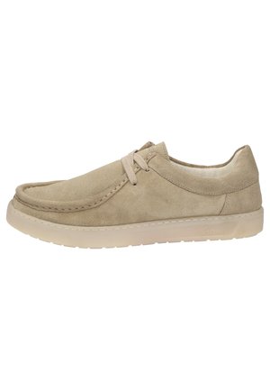 Beige suède sneaker met een gladde textuur, ronde neus, tonale veters en een lichte rubberen zool. Minimalistisch ontwerp zonder zichtbare patronen.