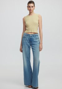 Top in maglina a coste khaki chiaro con orlo cropped abbinato a jeans a gamba larga blu chiaro, con classico design a cinque tasche.