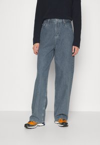 Vaaleansiniset leveälahkeiset farkut, joissa on korkea vyötärö, klassinen viisi-taskumalli ja hienovarainen kuluminen. Yhdistetty mustan teksturoituneen neuleen kanssa.