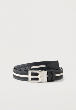 Ceinture en cuir noir avec une bande blanche et une boucle argentée en forme de lettre B, enroulée sur une surface blanche unie.