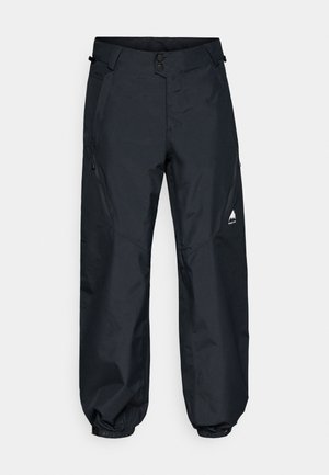 Pantalones impermeables negros con una textura suave, puños elásticos, bolsillos laterales con cremallera y un logo de montaña en la parte inferior de la pierna.