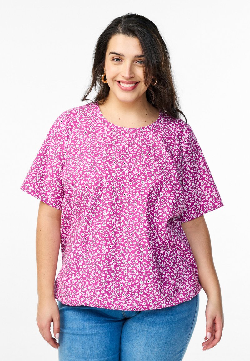 Blusa rosa a maniche corte con un motivo floreale in bianco e rosa chiaro. Girocollo e vestibilità comoda.