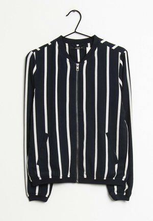 Tmavě modrá bomber bunda na zip s bílými svislými pruhy. Má elastické manžety a boční kapsy. Vyrobena z měkké, lehké látky.