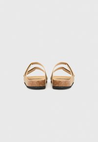 Brune korksandaler med to justerbare stropper, en flad sål og en tekstureret bagside for godt greb. Simpelt, minimalistisk design.