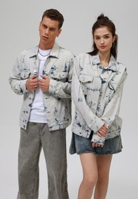 Vaatteet made in denim, joissa on siniset sitruunapainanteet, napit, rintataskut ja rento leikkaus, yhdistettynä vaaleansinisiin farkkuihin ja farkkuhameeseen.