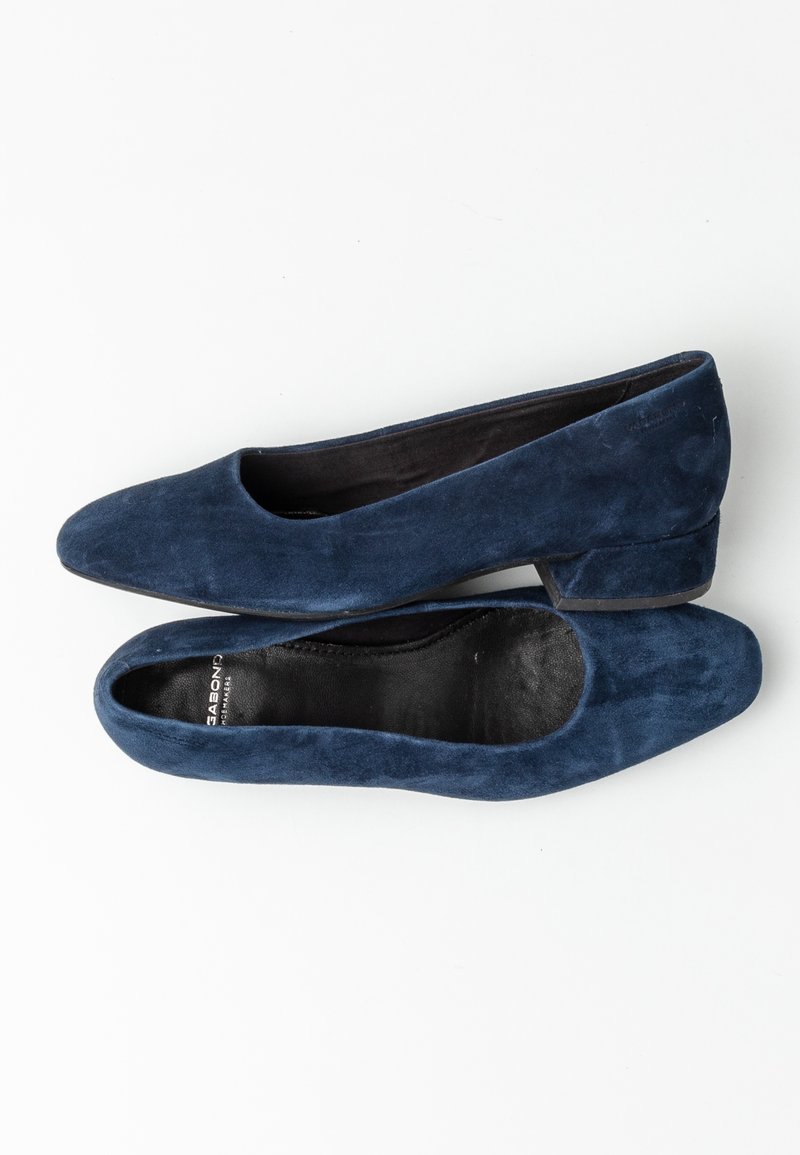 Marinblå mocka lägenheter med rundad tå, låg blockklack och en slät svart innersula. Minimalistisk design utan synliga detaljer.