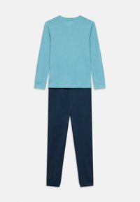 Világoskék hosszú ujjú ing kerek nyakkivágással és sötét tengerészkék nadrág. Mindkét darab puha, sima anyagból készült, egyszerű kialakítással.