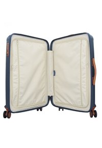 Maleta rígida navy con dos compartimentos, interior de tela crema, bolsillos con cremallera y detalles en cuero marrón. Cuenta con cuatro ruedas para fácil movilidad.