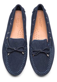 Námořnicky modré semišové mokasíny s kontrastním prošíváním, zavazovacím detailem vpředu a perforovanou stélkou pro prodyšnost. Uvnitř ražené logo značky.