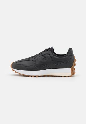 Baskets noires avec panneau latéral perforé, semelle intermédiaire blanche et semelle en caoutchouc marron avec crampons surélevés, vues de côté.