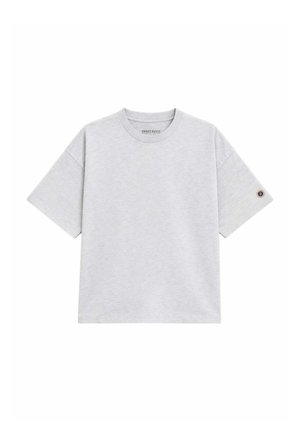 T-shirt gris clair à manches courtes avec col rond, petit écusson circulaire sur la manche gauche et étiquette "Sweet Pants" à l'intérieur du col.