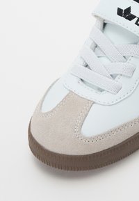 Svetlomodré tenisky s prémiovým špičkovým z nubukovej kože a syntetickým koženým zvrškom. Zahrňujú biele šnúrky a hnedú gumenú podrážku s textúrovaným vzorom.