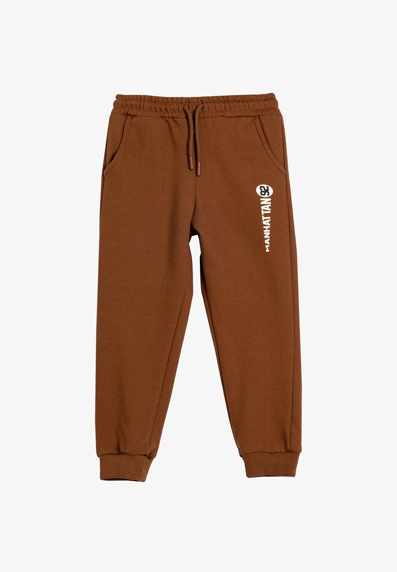 Brune sweats i blødt materiale med elastisk talje, sidelommer og et hvidt trykt logo på venstre forsiden.