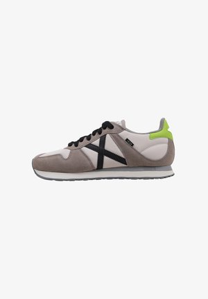 Sneakers con una parte superiore in suede grigio e pelle bianca, caratterizzate da una striscia diagonale nera, lacci neri e un accento sul tallone verde neon.