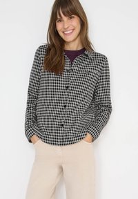 Czarna i biała koszula w kratę, wykonana z miękkiego materiału, z zapięciem na guziki z przodu, długimi rękawami i klasycznym kołnierzykiem.