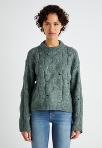 Maglione lavorato a maglia in tessuto verde testurizzato caratterizzato da motivi a onda e dettagli in pizzo, con un collo a girocollo a costine e maniche lunghe.
