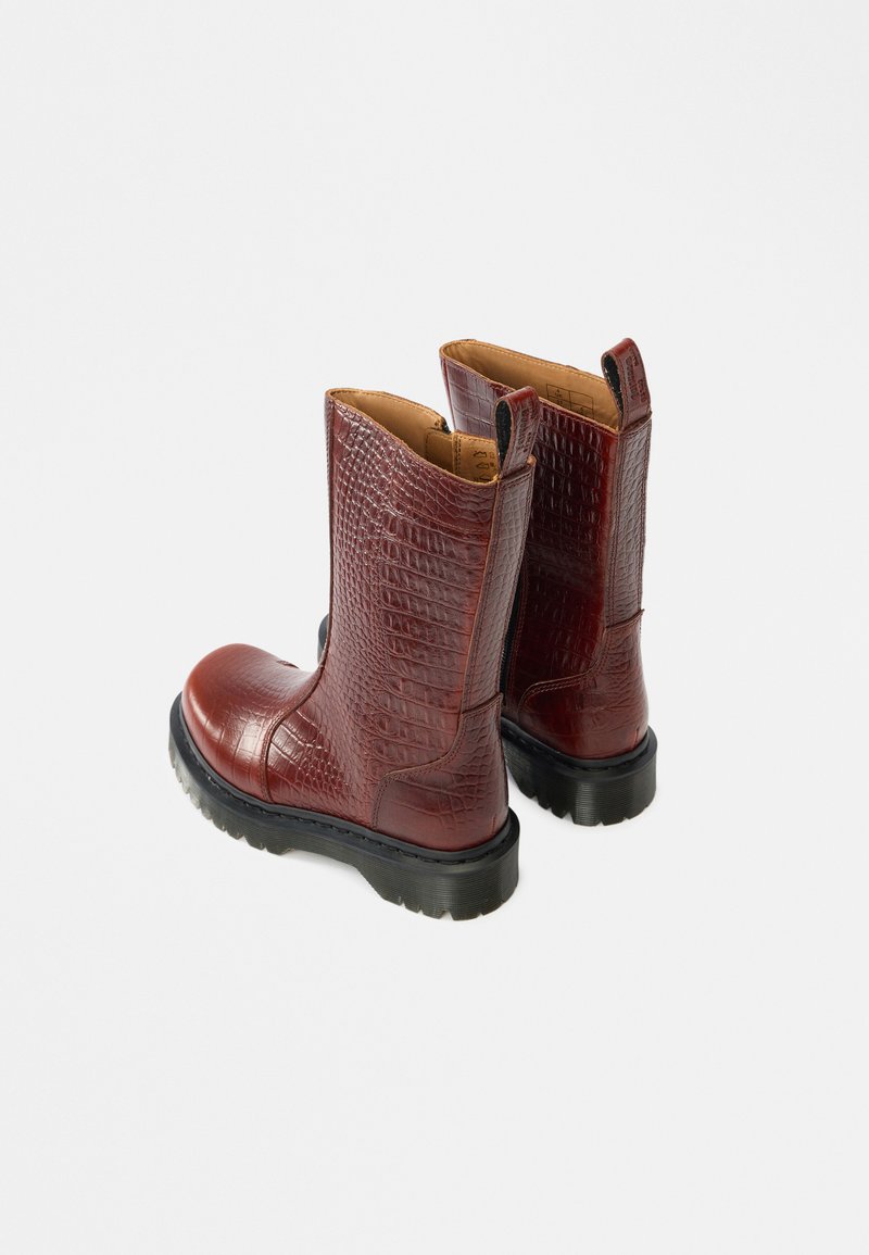 Burgundy crocodile-embossed leather ankle boots with a rounded toe and black rubber sole. Features pull tabs for easy wear.