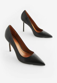 Scarpe nere in pelle con tacco alto, punta affusolata, texture liscia e tacchi a stiletto sottili. L'interno presenta tonalità marroni calde.