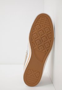 Beżowe płócienne trampki z teksturowaną gumową podeszwą. Posiadają białą środkową podeszwę, pomarańczowy akcent oraz bieżnik w diamentowy wzór dla lepszej przyczepności.