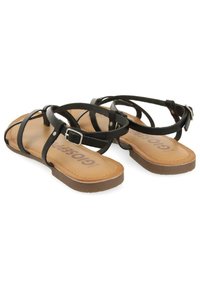 Sandali neri in pelle con cinturini sottili, fibbia regolabile, suola piatta color tan e logo impressa sulla soletta.