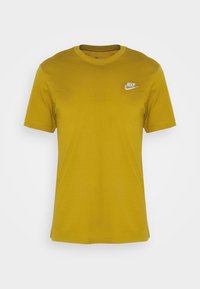 Žluté bavlněné tričko s klasickým kulatým výstřihem, krátkými rukávy a bílým logem Nike na levé hrudi. Hladká textura.