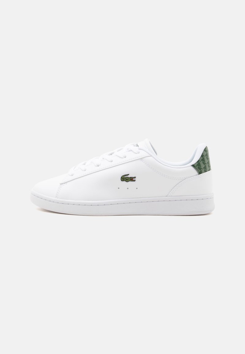 Baskets basses blanches avec logo crocodile vert sur le côté et languette de talon à motif vert, lacets blancs et semelle en caoutchouc plate.