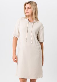 Robe beige clair en tissu doux, dotée d'une capuche, de manches courtes et de deux poches avant avec des coutures décoratives.