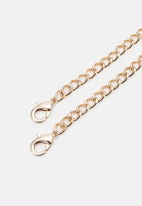 Złoty metalowy łańcuch z dużymi owalnymi ogniwami i dwoma zapięciami karabińczykowymi na każdym końcu. Gładka tekstura i błyszczące wykończenie; bez wzorów.