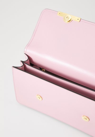 Borsa a tracolla in pelle rosa con una texture liscia, dotata di hardware dorato, chiusura magnetica e una tasca interna con zip.