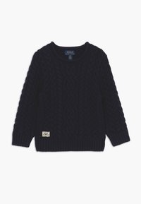 Syvä sininen neulepaita, jossa on vaijerikuviointi, pyöreä pääntie, ribbikuvioidut hihansuut ja helma, jossa on pieni merkki alareunassa.