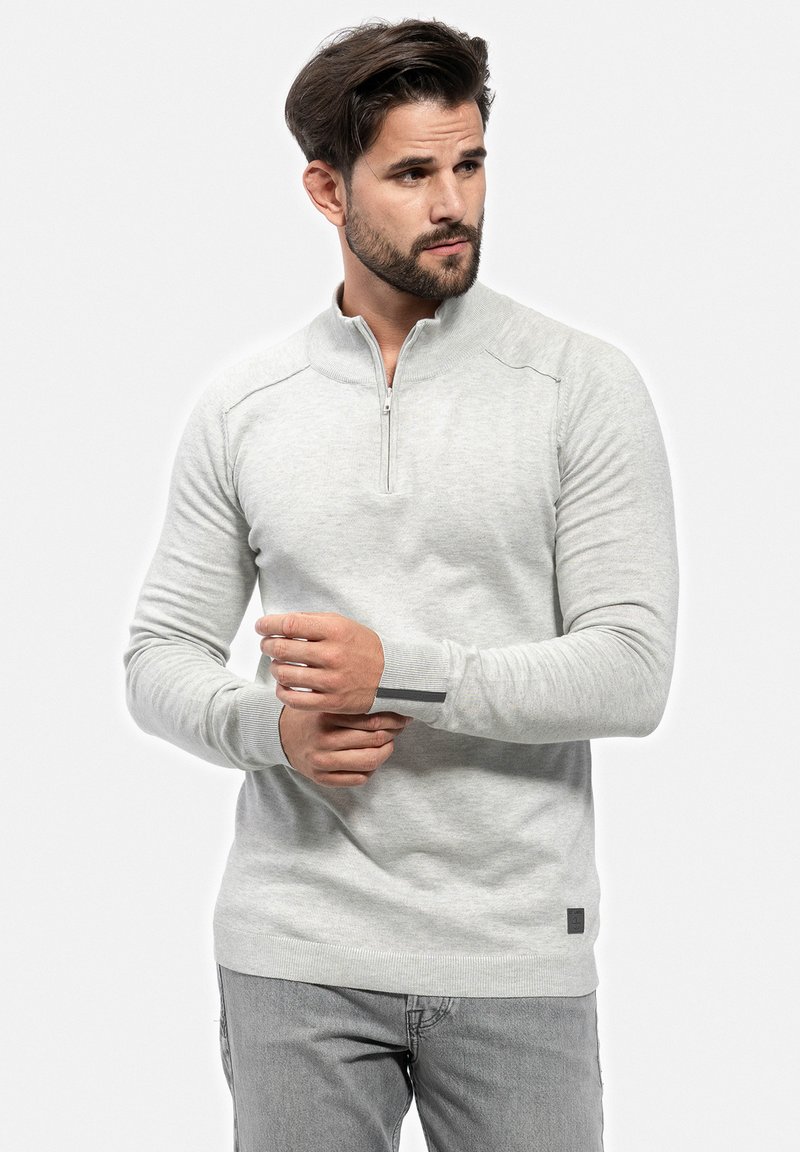 Cardigan zip grigio chiaro in morbidissimo materiale a maglia, con colletto alto, polsini a costine e un piccolo etichetta con il marchio sull'orlo.