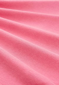 Tissu en coton rose avec une texture lisse, présentant des plis doux et un motif de tissage uniformément réparti sur la surface.