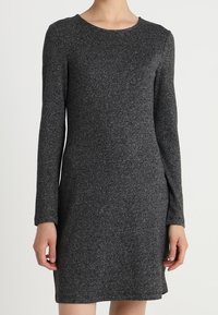 Abito a maniche lunghe di colore grigio scuro, realizzato in tessuto testurizzato. Caratterizzato da un collo rotondo e una silhouette aderente, che arriva sopra il ginocchio.