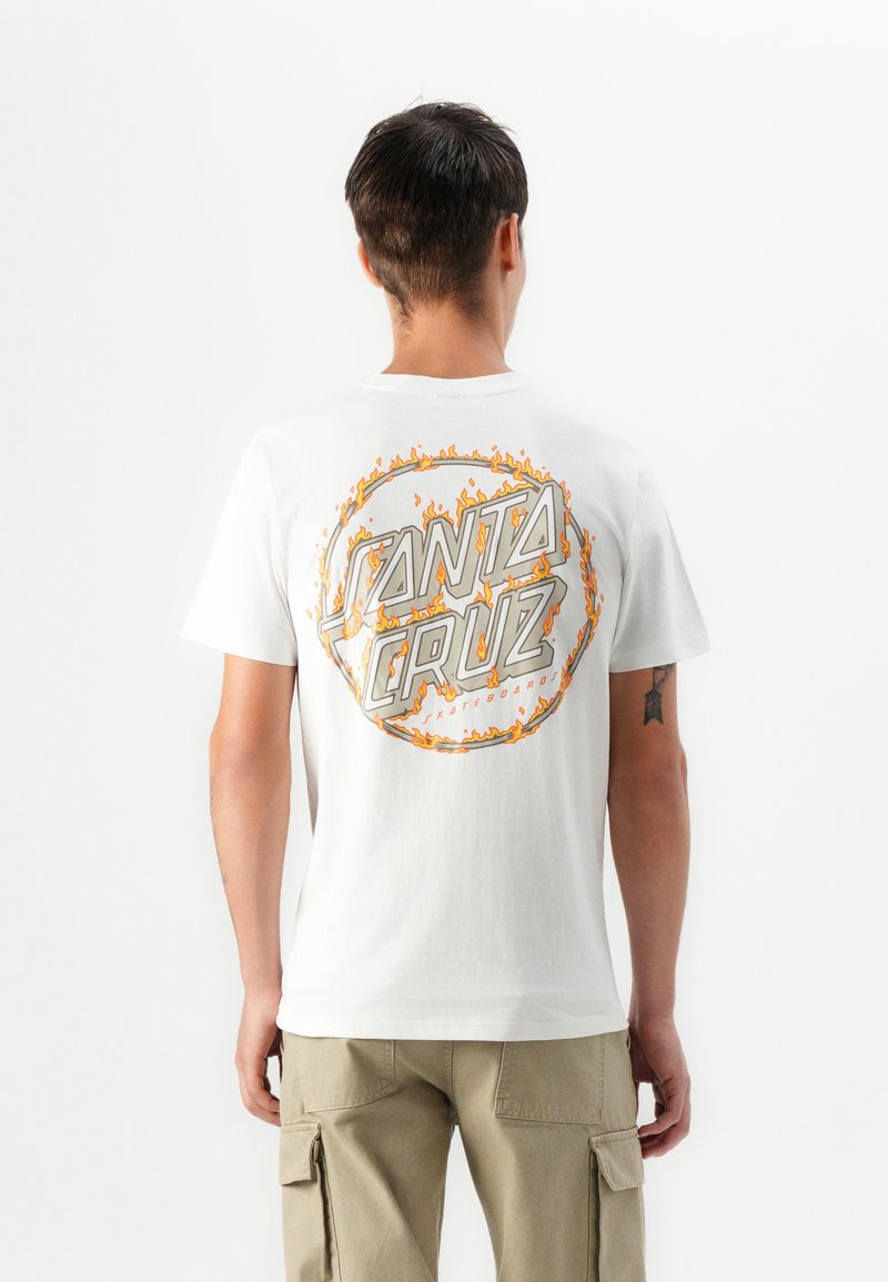 Hvid bomulds t-shirt med et cirkulært orange flamme design, prydet med teksten "SANTA CRUZ" og "SKATEBOARD" i grå, set bagfra.