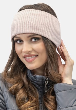 Fascia di testa a coste di un delicato rosa chiaro, ampia e con una texture liscia, indossata con una giacca grigia scura con zip. Il modello tocca delicatamente la fascia.
