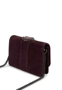 Ciemnofioletowa torebka na ramię z zamszowego materiału o teksturowym wykończeniu, z łańcuszkowym paskiem i dekoracyjnym zapięciem z metalowymi oraz kamieni szlachetnych akcentami.