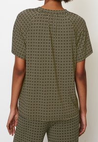 Top de manga corta verde con un diseño estampado, de escote redondo, que presenta un diseño floral y un corte holgado. Tejido suave con una textura lisa.