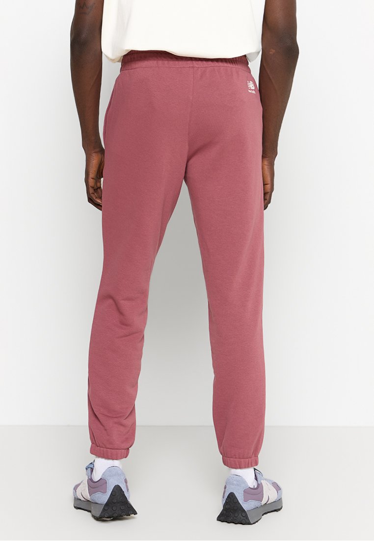Bordeauxfarbene Sporthose mit elastischem Bund, elastischen Bündchen an den Knöcheln und einem kleinen Logo-Detail auf der Rückseite. Weicher Stoff mit glatter Textur.