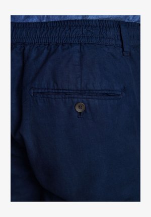 Pantalones cortos azul marino con cintura elástica y un bolsillo trasero con cierre de botón marrón. El material parece ligero y suave.